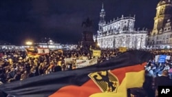 FILE - Members of the Patriotic Europeans against the Islamization of the West hold German flags and lights during a demonstration near the Dresden Cathedral in Dresden, Germany, Dec. 22, 2014. 