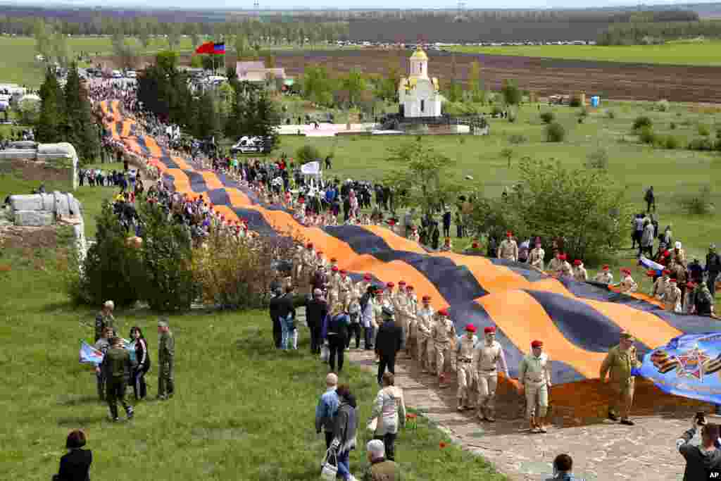 Activists carry a 300-meter-long St. George ribbon, which has become a symbol of the pro-Russian insurgency in eastern Ukraine, during celebrations of the Victory Day at a World War II memorial in Saur-Mogila, about 60 km (31 miles) east of Donetsk, May 8, 2021.