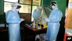 Des travailleurs de la santé avec un équipement de protection contre Ebola dans un centre de traitement à Bikoro, RDC, 13 mai 2018.