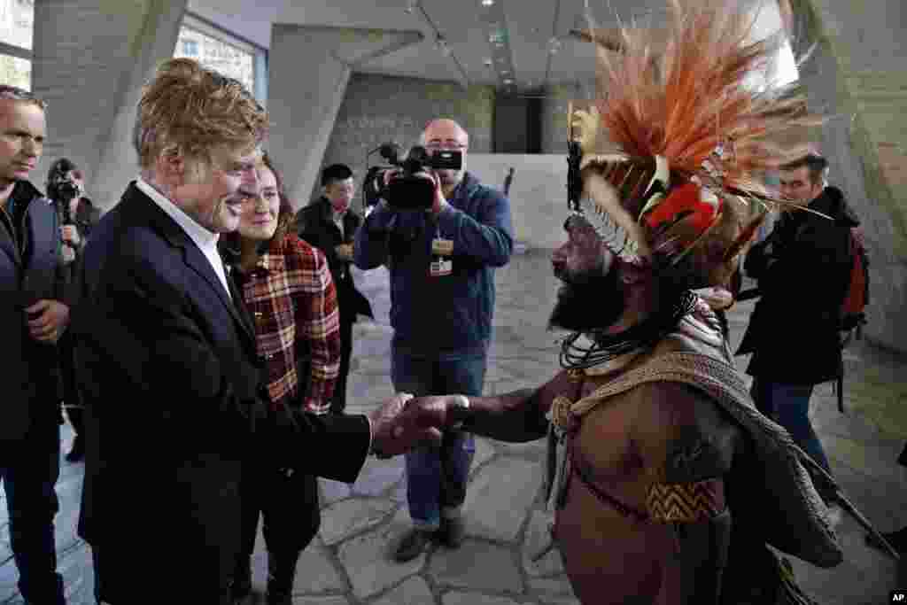 Un chef de la tribu Huli de Papouasie-Nouvelle-Guinée, Mundiya Kepanga, à droite, se serre la main avec l&#39;acteur américain et militant écologiste Robert Redford, avant une conférence sur le climat, au siège de l&#39;UNESCO, à Paris, 6 décembre 2015.&nbsp;