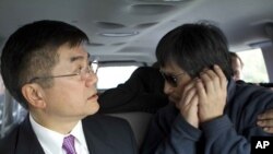 In this photo released by the US Embassy Beijing Press Office, blind lawyer Chen Guangcheng makes a phone call as he is accompanied by U.S. Ambassador to China Gary Locke in a car on the way to a hospital in Beijing, May 2, 2012. 