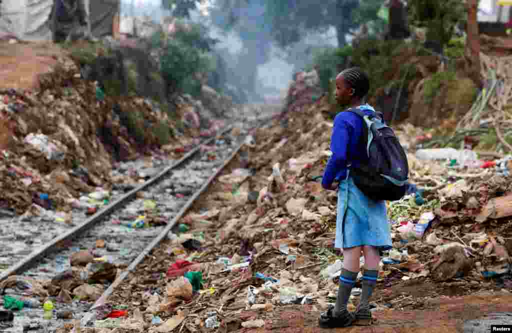 A schoolgirl stands next to the Kenya-Uganda railway line during the partial reopening of schools, due to the COVID-19 pandemic, in Kibera slums of Nairobi, Kenya.