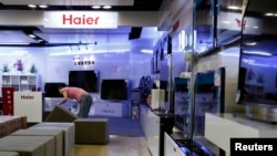 FILE - An employee arranges stools at a section displaying Haier television sets inside a Suning store in Shanghai.