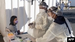 Des agents de santé portant des équipements de protection individuelle se préparent à tester une femme pour le COVID-19 au Fourways Life Hospital de Johannesburg le 28 juin 2021.