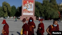 一群年轻的尼姑在拉萨的布达拉宫广场走过有着包括习近平在内的中国领导人的画像。（2021年10月15日）