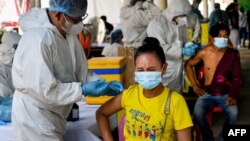 FILE - Health officials in personal protective equipment (PPE) inoculate people with the second dose of China's Sinopharm Covid-19 coronavirus vaccine at a pagoda in Phnom Penh on May 20, 2021, as part of the government's campaign to halt the rising number of cases. (AFP)