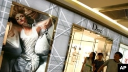 ຊາວຈີນຄອບຄົວນຶ່ງ ພວມຍ່າງອອກມາຈາກຮ້ານຂາຍເຄື່ອງ Dior ທີ່ນະຄອນຫຼວງປັກກິ່ງ (13 ມີນາ 2012) 