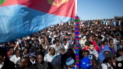FILE - An African migrant holds an Eritrean flag during a protest outside Israel's parliament in Jerusalem, Jan. 8, 2014. The fledgling peace between Ethiopa and Eritrea is raising new questions for Eritrea's diaspora, tens of thousands of people who fled the Eritrean government's tight grip, a rigid compulsory military and endemic poverty.