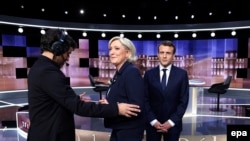 France - French presidential election candidate Marine Le Pen (2ndL) and French presidential election candidate Emmanuel Macron (R) arrive to pose prior to the start of a live brodcast face-to-face televised debate in television studios, Paris, May 03, 2017