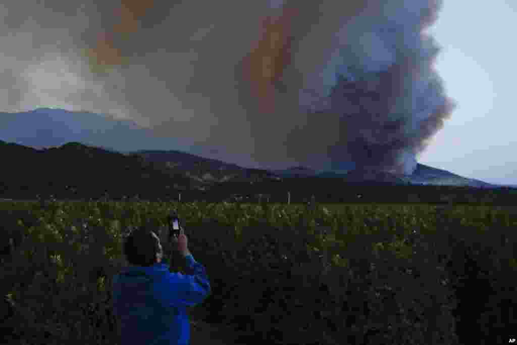 Lupe Robles uses his phone to take pictures of a huge plume of smoke from a wildfire in Santa Paula, California, Dec. 7, 2017. 