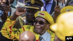 In this file photo taken on Nov. 8, 2017, Zimbabwe's then-President Robert Mugabe raises his fist as he greets party members and supporters gathered at his party headquarters. 