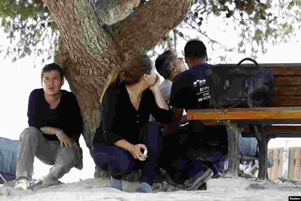 Israeli civilians and journalists take cover during an air raid attack near the Israeli Gaza border as rockets are fired from Gaza to Israel, August 8, 2014.