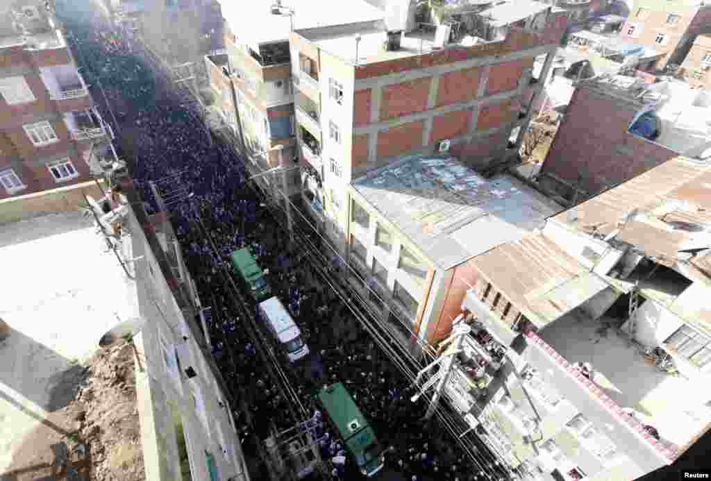 Thousands walk behind the vehicles carrying the coffins of the three Kurdish activists shot in Paris during their funeral ceremony in Diyarbakir, Turkey, January 17, 2013. 