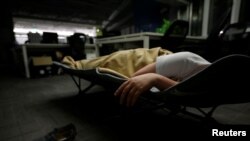 A system engineer at RenRen Credit Management Co., sleeps on a camp bed at the office