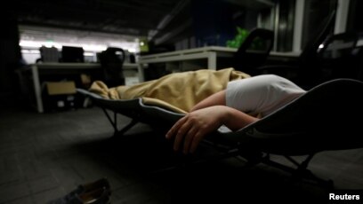 A system engineer at RenRen Credit Management Co., sleeps on a camp bed at the office
