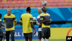 FILE - Cameroon's Pierre Webo, right, controls a ball during an official training session at the Arena da Amazonia in Manaus, Brazil, June 17, 2014. Many African youngsters dreaming of becoming wealthy football stars abroad face an uphill battle, a new report finds.