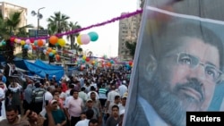 FILE - Members of the Muslim Brotherhood and supporters of deposed Egyptian President Mohamed Morsi hold a giant poster bearing his image at a protest in Cairo's Rab'a al-Adawiya Square, Aug. 8, 2013.