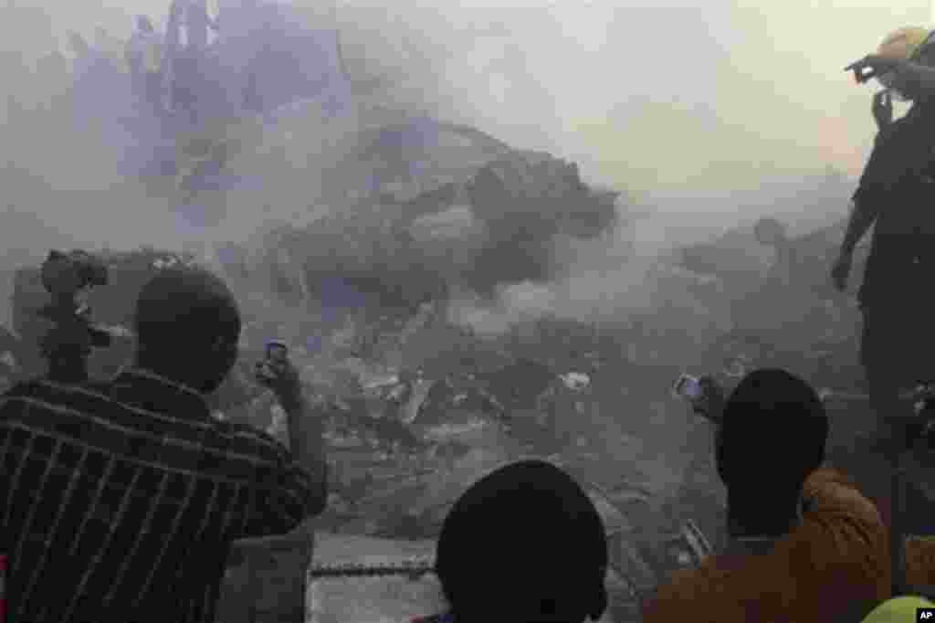 People use their mobile phones to take photos of the wreckage of a Dana Airlines plane crash in Lagos, Nigeria, Sunday, June 3, 2012.