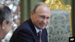 ປ. ຣັດເຊຍ ທ່ານ Vladimir Putin ນັ່ງຍິ້ມ ໃນຂະນະທີ່ໂອ້ລົມ ກັບລັດຖະມົນຕີການຕ່າງປະເທດ ທ່ານ Sergey Lavrov, ຊ້າຍ, ໃນກອງປະຊຸມດ້ານຄວາມປອດໄພ ຂອງພາກພື້ນ ຫຼື (CSTO) ທີ່ Dushanbe, Tajikistan, 15 ກັນຍາ, 2015.