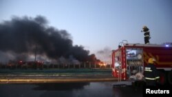 Firefighters work at the site as smoke rises from the debris after the explosions at the Binhai new district in Tianjin, China, Aug. 13, 2015. 