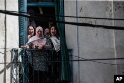 Women react from their balconies as police clash with protesters during a demonstration against the country's leadership in Algiers, April 12, 2019.