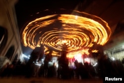 FILE - Shiite Muslims perform with fire during commemorations for Ashoura in Najaf, Oct. 9, 2016.