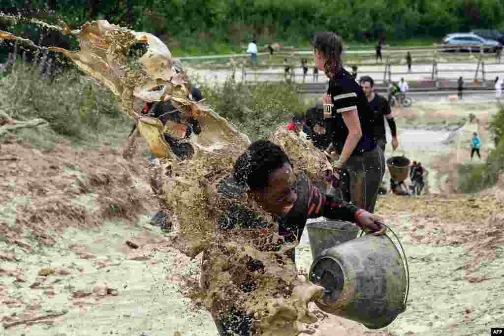 Lumpur dilemparkan kepada para pelari saat mereka ikut serta dalam apa yang disebut sebgaai Mud Day, sebuah perlombaan yang berjarak 13 km dengan berbagai rintangannya di Beynes, dekat Paris, Perancis, 16 Juni 2019.