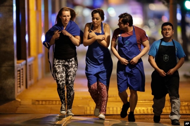 Personas en el área de uno de los ataques del sábado por la noche en Londres salen de la zona de cordon policial.