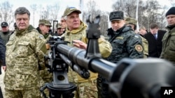 Ukraine's President Petro Poroshenko, left, followed by officials, listens to a weapons expert as he inspects weapon systems for the Ukrainian Army at a military base in Novi Petrivtsi outside Kiev, Ukraine, April 4, 2015. 