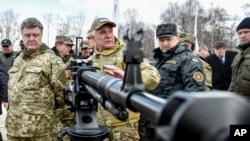 FILE - Ukraine's President Petro Poroshenko, left, followed by officials, listens to a weapons expert as he inspects weapon systems for the Ukrainian Army at a military base in Novi Petrivtsi outside Kiev, Ukraine, April 4, 2015. 