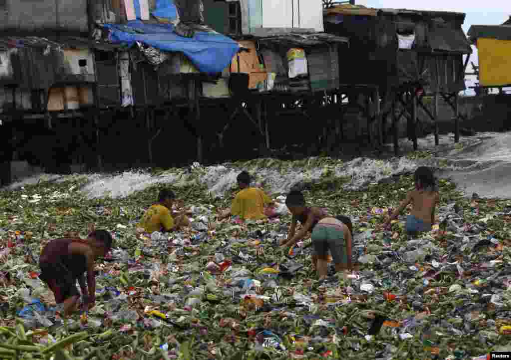Mali Filipinci iz sirotinjskog naselja u blizini luke u Manili preturaju po plutajućem otpadu tragajući za otpacima pogodnim za reciklažu.