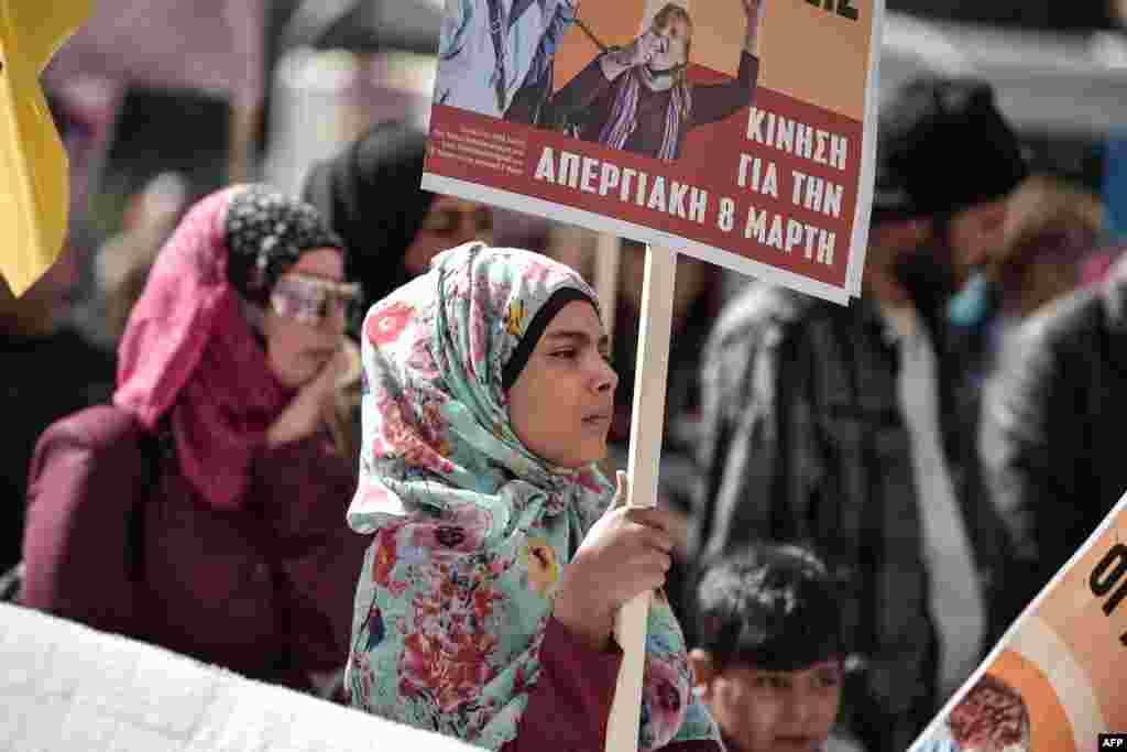 A migrant girl holds a placard as she takes part in a march in central Athens on March 8, 2019 during a women's strike to mark the International Women's Day.