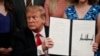 FILE - President Donald Trump holds up an executive order in the East Room of the White House, in Washington, March 21, 2019.