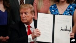 FILE - President Donald Trump holds up an executive order in the East Room of the White House, in Washington, March 21, 2019.