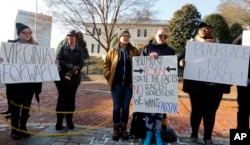 Demonstrators hold signs and chant outside the Governor's Mansion in Richmond, Va., Feb. 2, 2019. The demonstrators were calling for the resignation of Virginia Gov Ralph Northam after a decades-old, racially insensitive photo from his medical school yearbook page was widely distributed Friday.