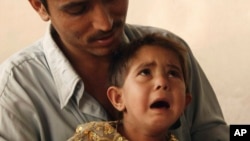 FILE - Parvez holds his 3-year-old daughter Sunam, who is dressed in the outfit she wore for the party in which she was engaged to her seven-year-old cousin, Nieem, in Kabul, Afghanistan, July 11, 2007.