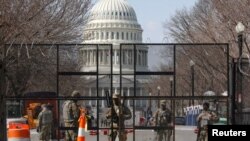 Des soldats de la Garde nationale montent la garde derrière une barrière de sécurité au Capitole à Washington, le 4 mars 2021. 