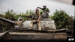 Para prajurit Angkatan Bersenjata Republik Demokratik Kongo (FARDC) memberi isyarat saat mereka menaiki tank saat mereka maju menuju Sake, 25 km di barat laut Goma pada 23 Januari 2025. (Foto: AFP)