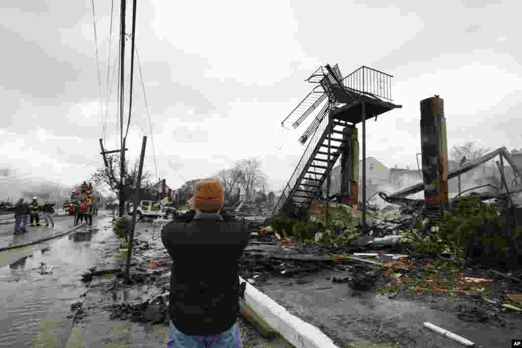 A man photographs damage caused by a fire fire in the Belle Harbor neighborhood in the New York City borough of Queens Oct. 30, 2012, in New York.