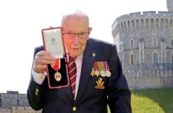 FILE - In this July 17, 2020, photo, Captain Tom Moore poses for the media after receiving his knighthood from Britain's Queen Elizabeth, during a ceremony at Windsor Castle in Windsor, England.