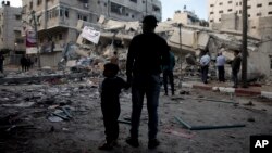 Palestinians stand in front of a destroyed multi-story building was hit by Israeli airstrikes in Gaza City, May 5, 2019. 