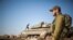 FILE - Israeli soldiers gather next to their tanks near the border with Syria in the Israeli-controlled Golan Heights, Nov. 28, 2016. 