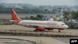 Seorang petugas keamanan berjaga di dekat Airbus A-320 Air India di Bandara Begumpet, Hyderabad,14 Maret 2020. (Foto oleh NOAH SEELAM / AFP)
