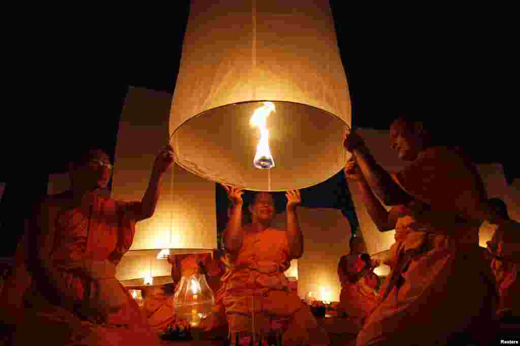 Buddhist monks release paper lanterns into the sky in Suphan Buri province, Thailand, to pay homage to Lord Buddha and bless the country as it enters the new year. 