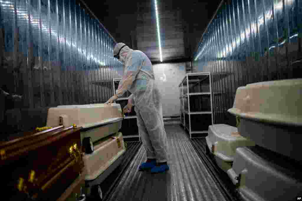 An AVBOB mortuary employee wearing full PPE checks coffins containing the remains of COVID-19 victims in a refrigerated container in Johannesburg, South Africa.
