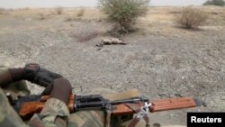 Soldats tchadiens en voiture devant le corps d'un combattant présumé de Boko Haram à Gambaru, au Nigeria, le 26 février 2015.