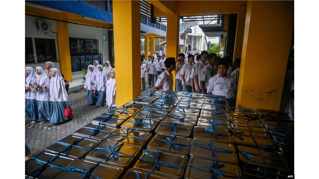 Para siswa berkumpul untuk menerima kotak makan siang pada hari pertama program makan gratis di SMA Muhammadiyah di Sidoarjo, 6 Januari 2025. (Juni KRISWANTO / AFP)