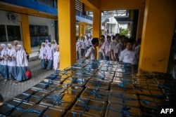 Para siswa berkumpul untuk menerima kotak makan siang pada hari pertama program makan gratis di SMA Muhammadiyah di Sidoarjo, 6 Januari 2025. (Juni KRISWANTO / AFP)