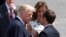 FILE - French President Emmanuel Macron shakes hands with U.S. President Donald Trump as first lady Melania Trump looks on after the traditional Bastille Day military parade in Paris, July 14, 2017. 