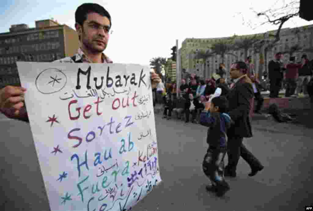 A man carries a placard, written in several languages and reading: "Mubarak, Get Out" referring to Egyptian President Hosni Mubarak, as he attends a demonstration by anti-government protesters in Cairo's Tahrir Square, Egypt, Monday, Jan. 31, 2011. A coal